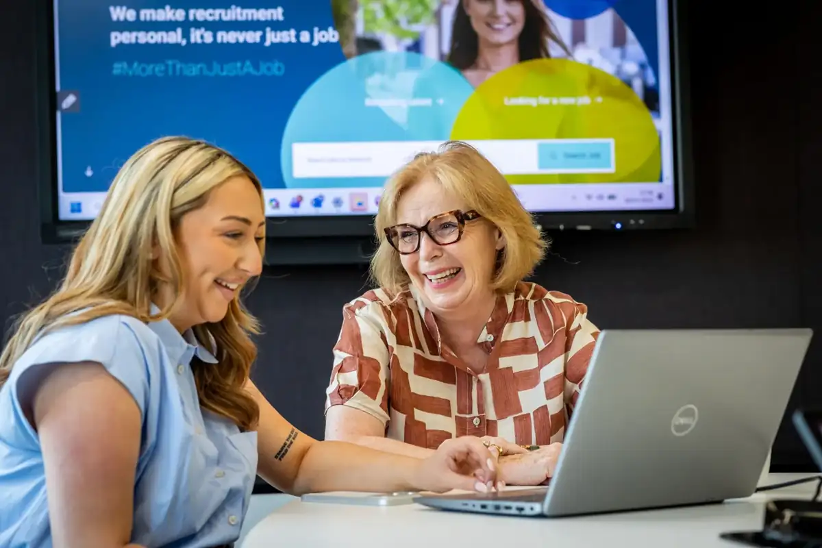 Two colleagues using a laptop together to complete work