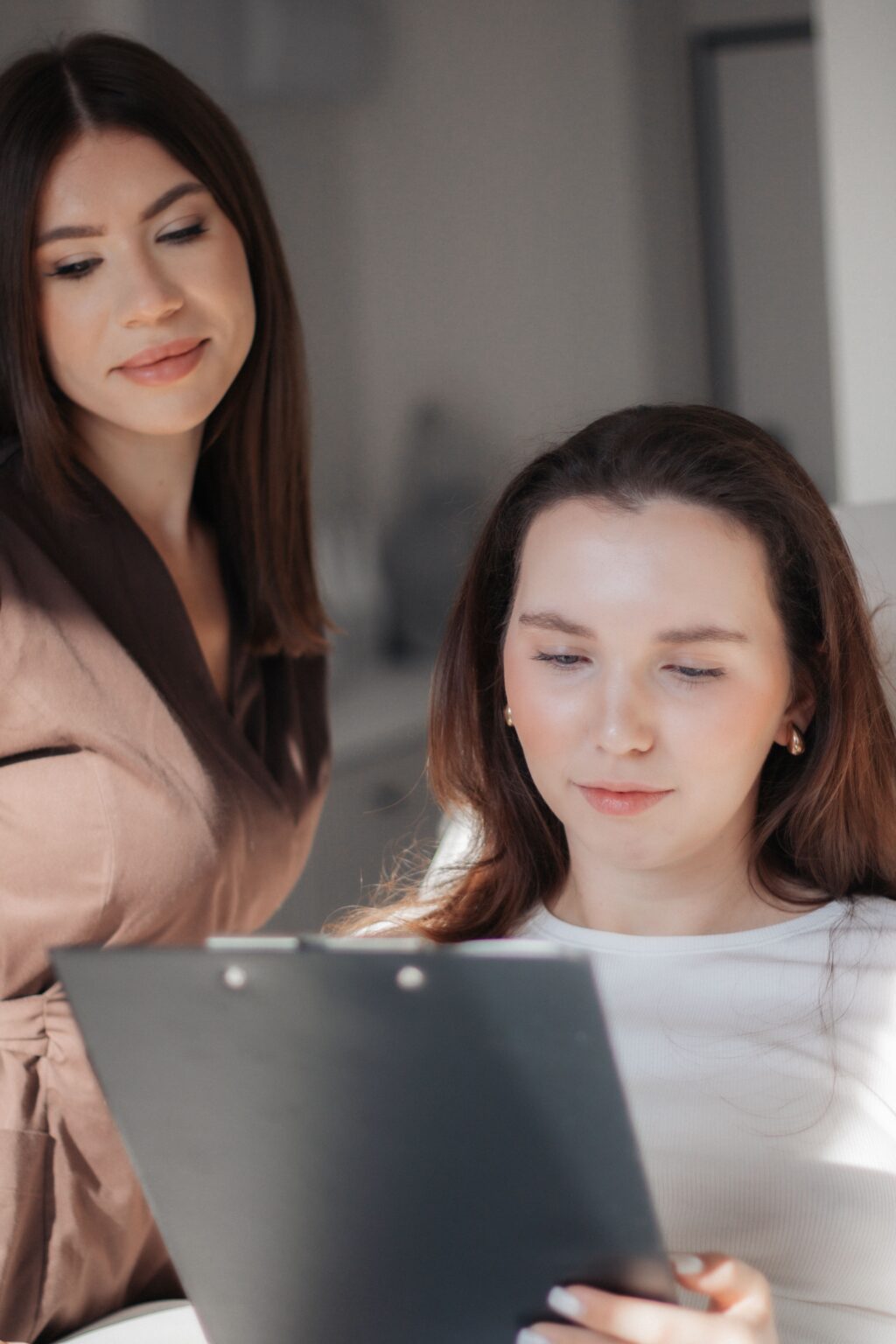 Two colleagues reviewing information on a clipboard in an office