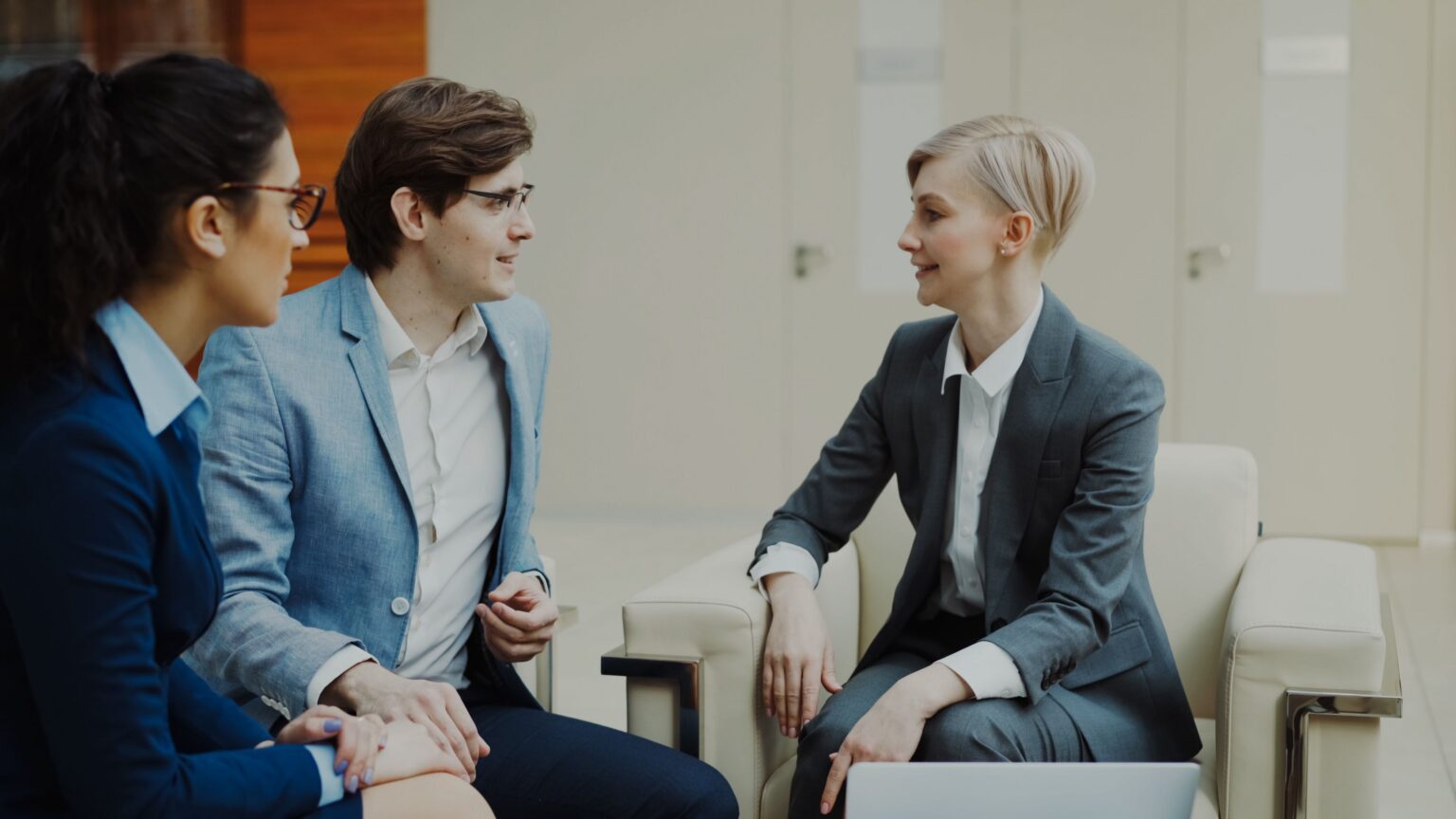 Colleagues in business attire talking together in a modern office lounge